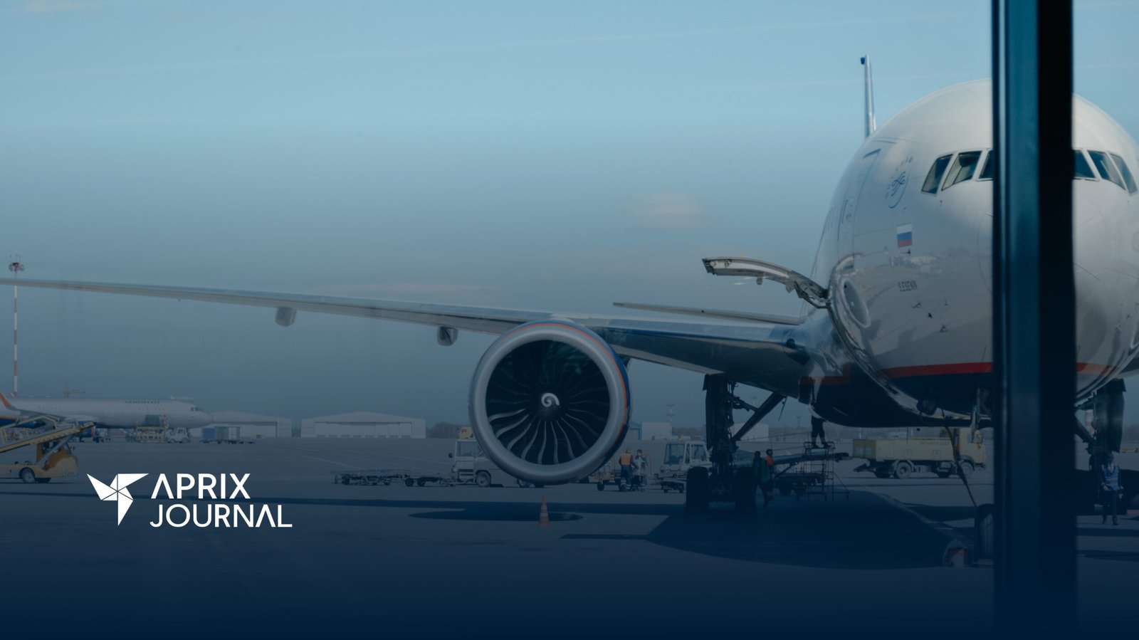A imagem mostra a visão de frente da turbina de um avião, por trás da janela de um aeroporto